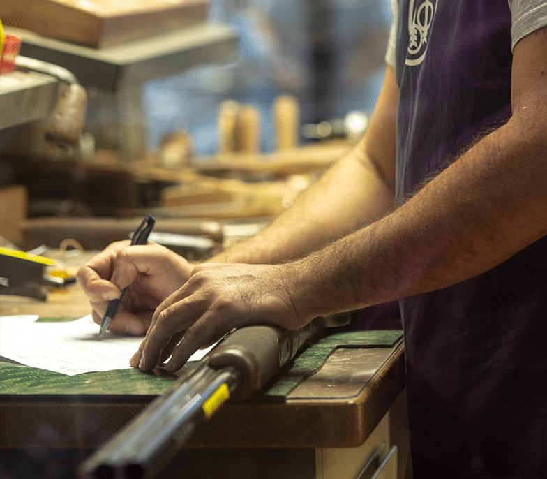 Gunsmith works on firearm at desk